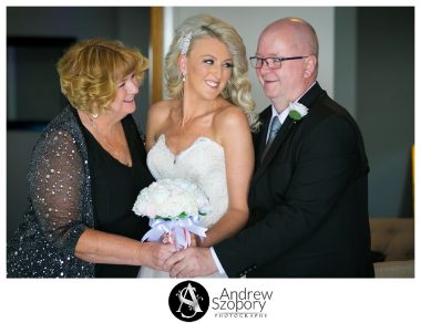 bride and mum looking at dad laughing during family photo