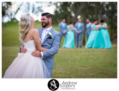 Bride and groom laughing as they interact with bridal part in the background