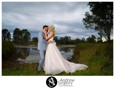 dramatic formal picture of bride and groom hugging by the dam