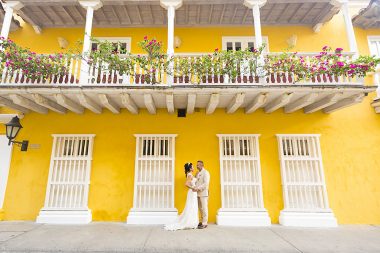 Bride and groom stand in front of colourful house in Cartagenta at El Marques