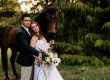 bride and groom stand with a horse on wedding day