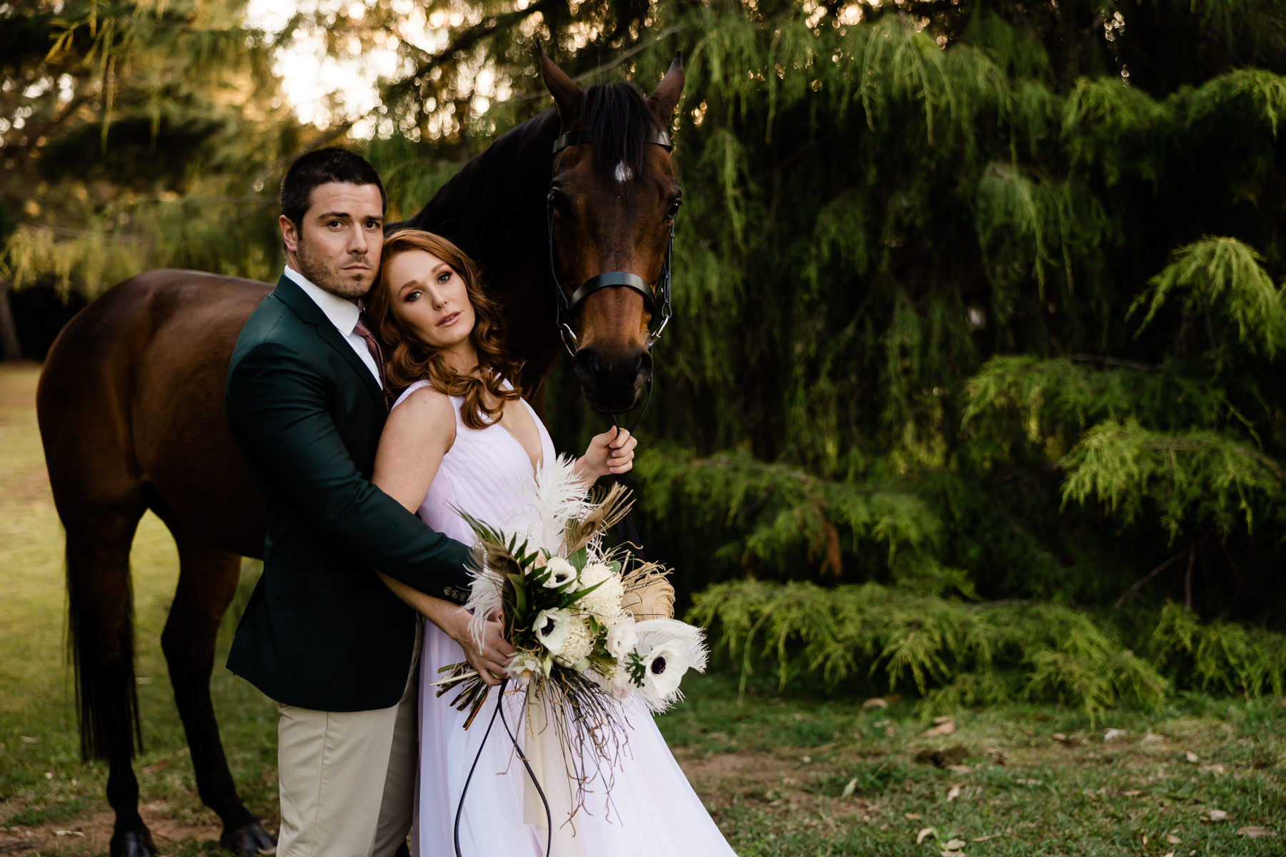 bride and groom stand with a horse on wedding day